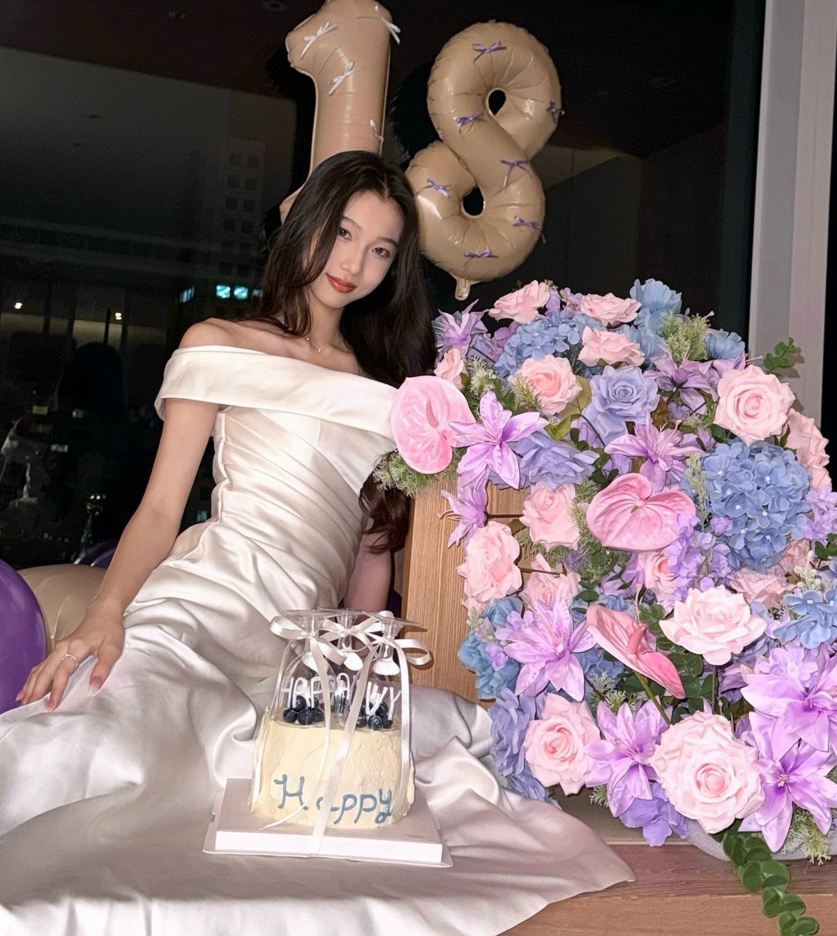 Young woman in white satin gown with 18 balloons and floral bouquet