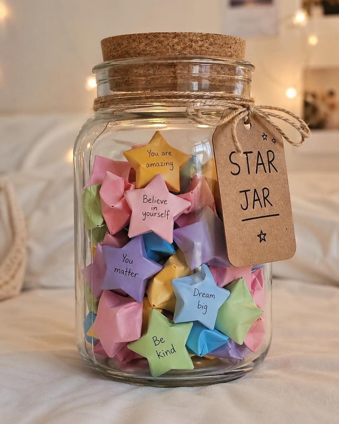 Glass jar filled with colorful folded paper stars and a Star Jar tag.