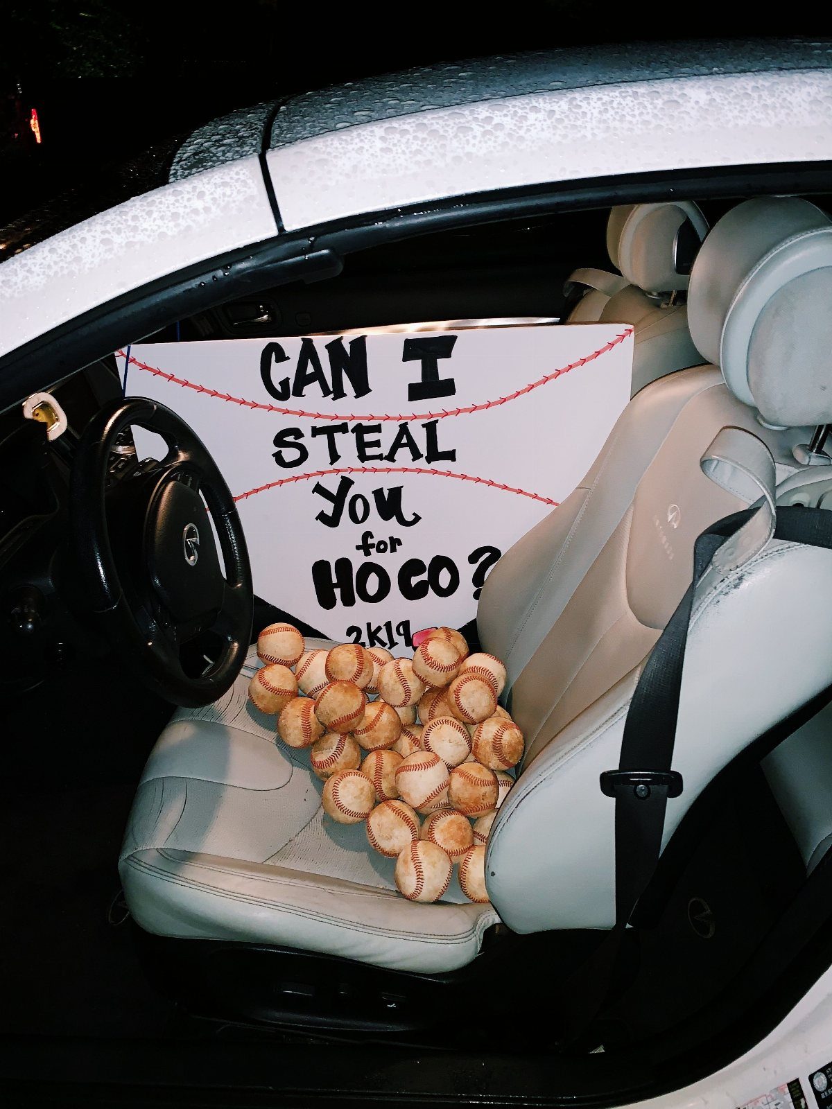Baseball homecoming proposal sign and baseballs on a car passenger seat