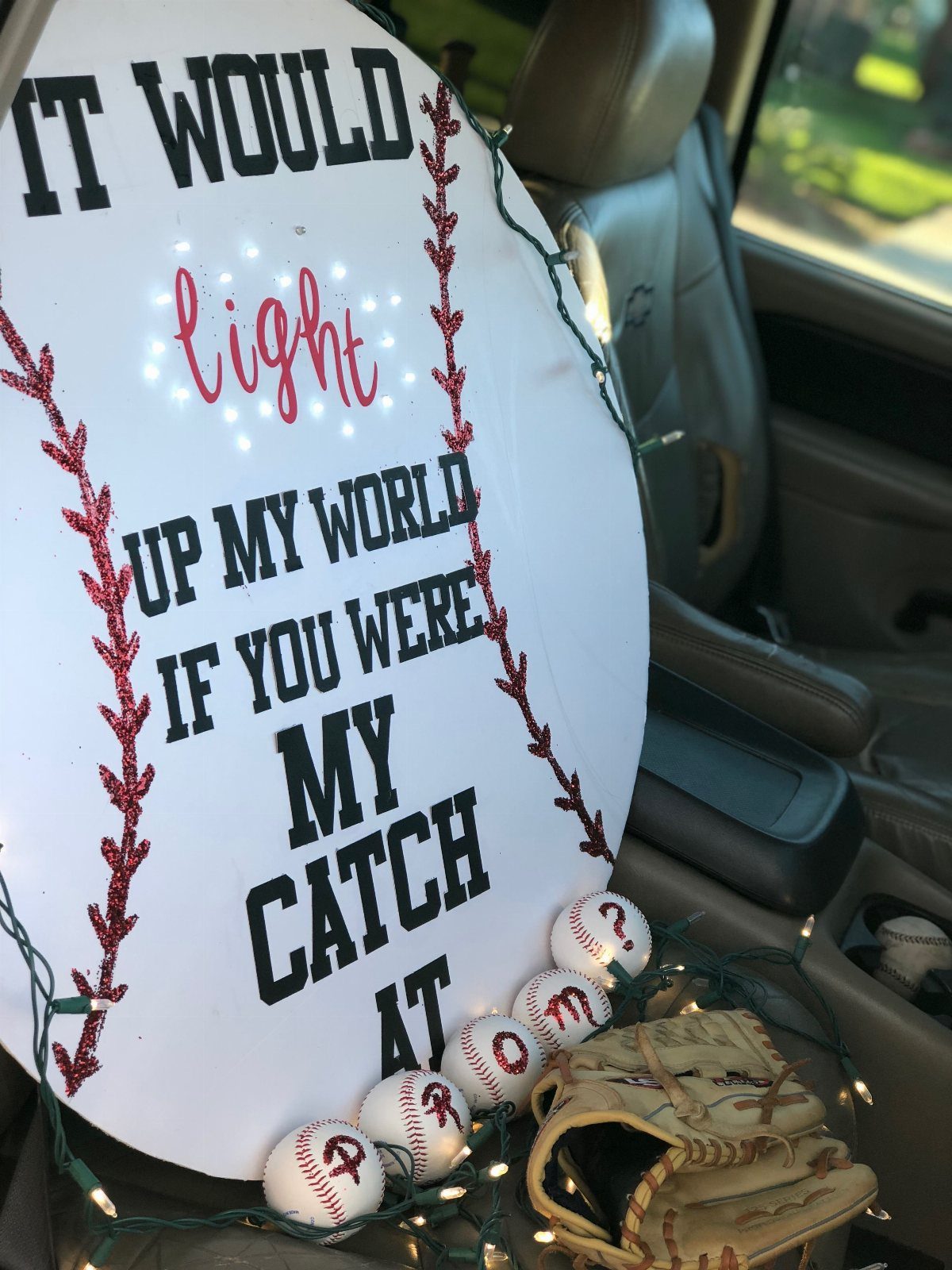 Baseball shaped homecoming proposal sign with lights, baseballs, and a leather glove.