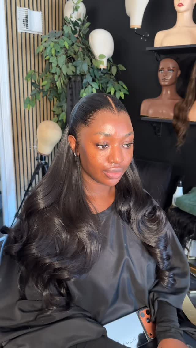 Woman with long dark curled hair styled in a half-up half-down look.