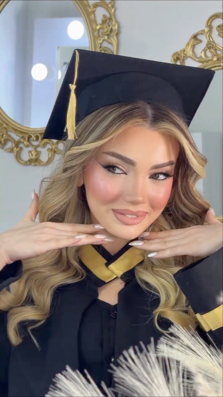 Woman in graduation cap and gown with long blonde loose waves hair.