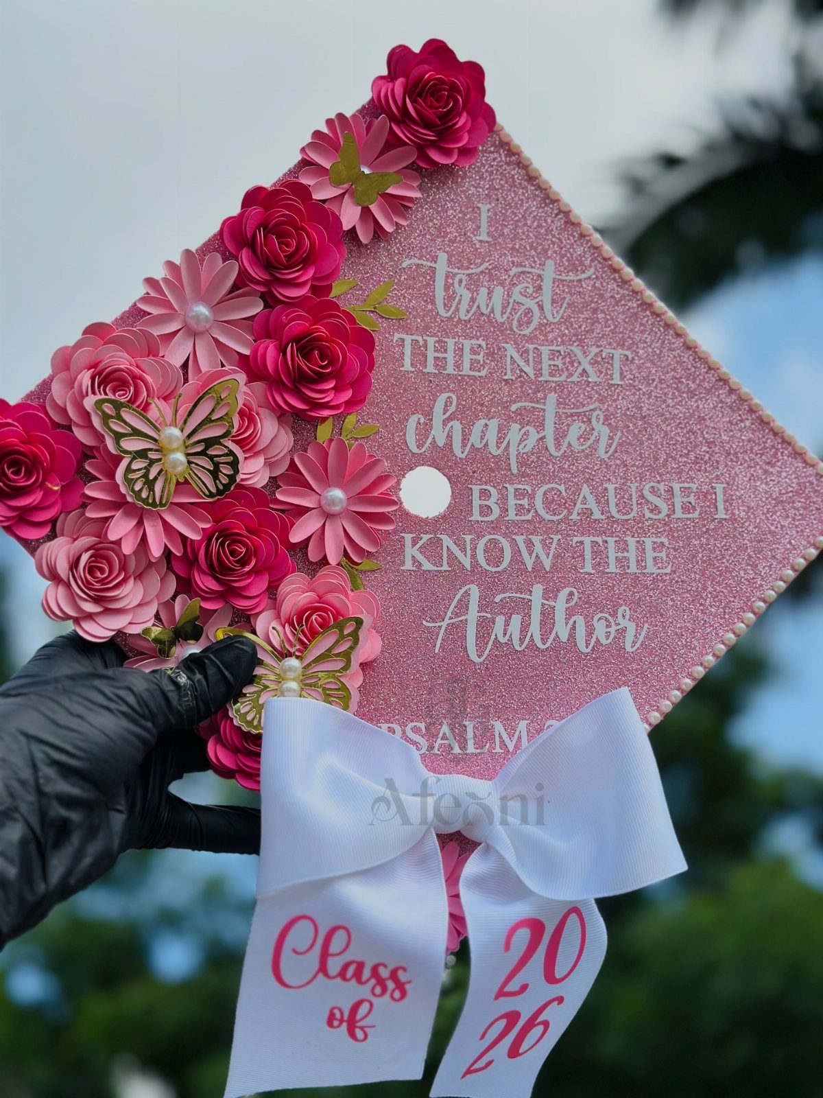 Pink glittery graduation cap decorated with 3D roses, butterflies, and inspirational text.