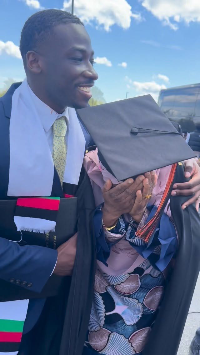 Graduating student in a suit and stole hugging a family member in cap and gown