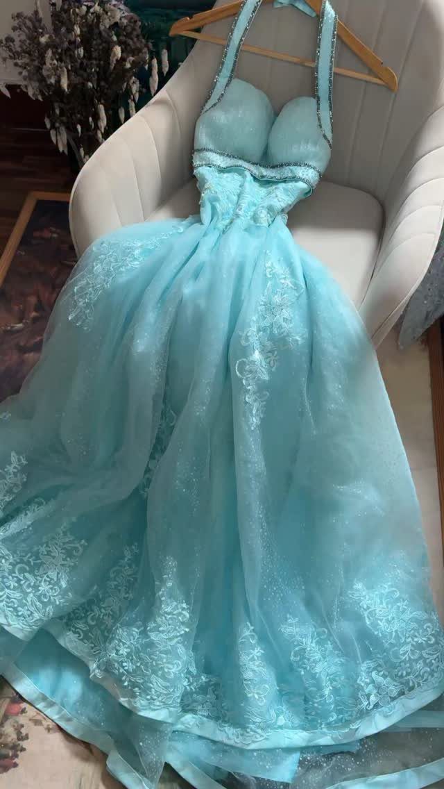 Light blue lace prom dress hanging on a wooden hanger over a white chair
