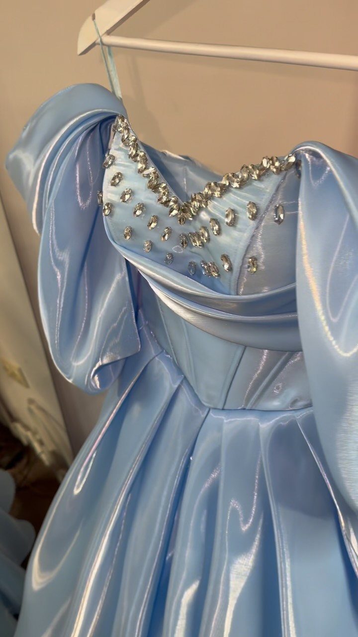 Light blue satin prom dress with beaded neckline hanging on a white hanger