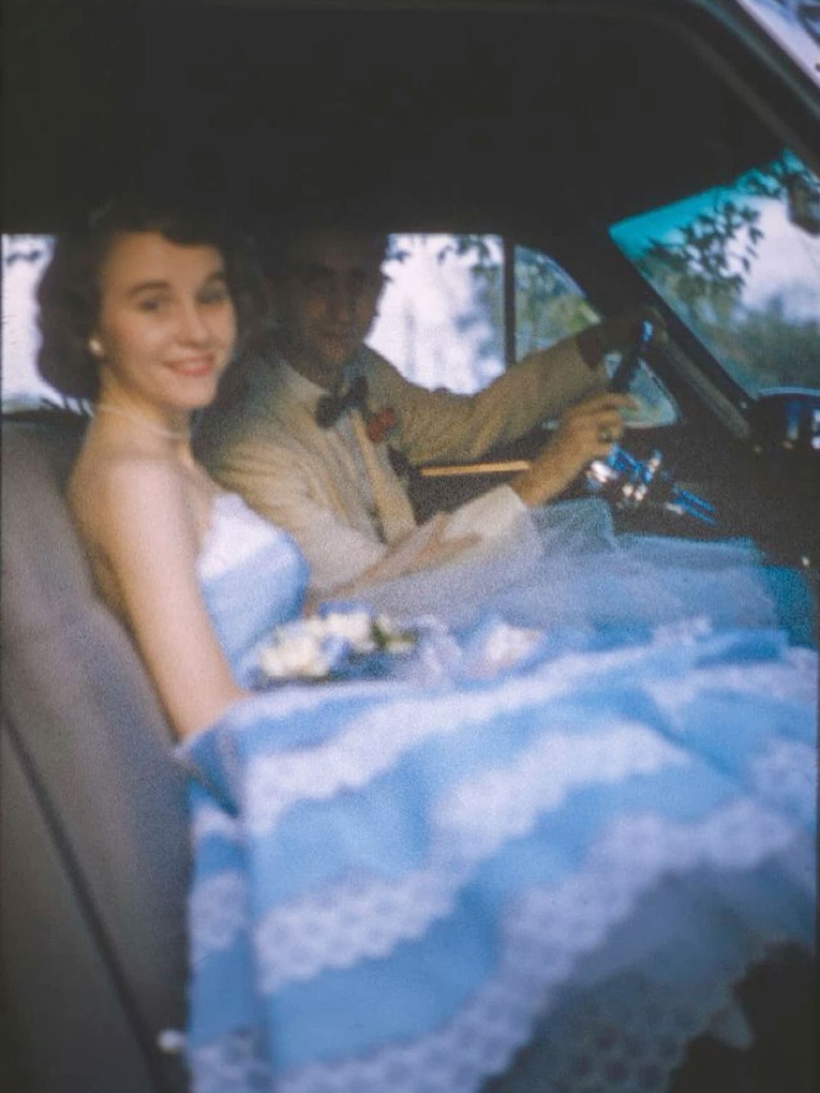 Young couple in vintage formal wear sitting inside a classic car