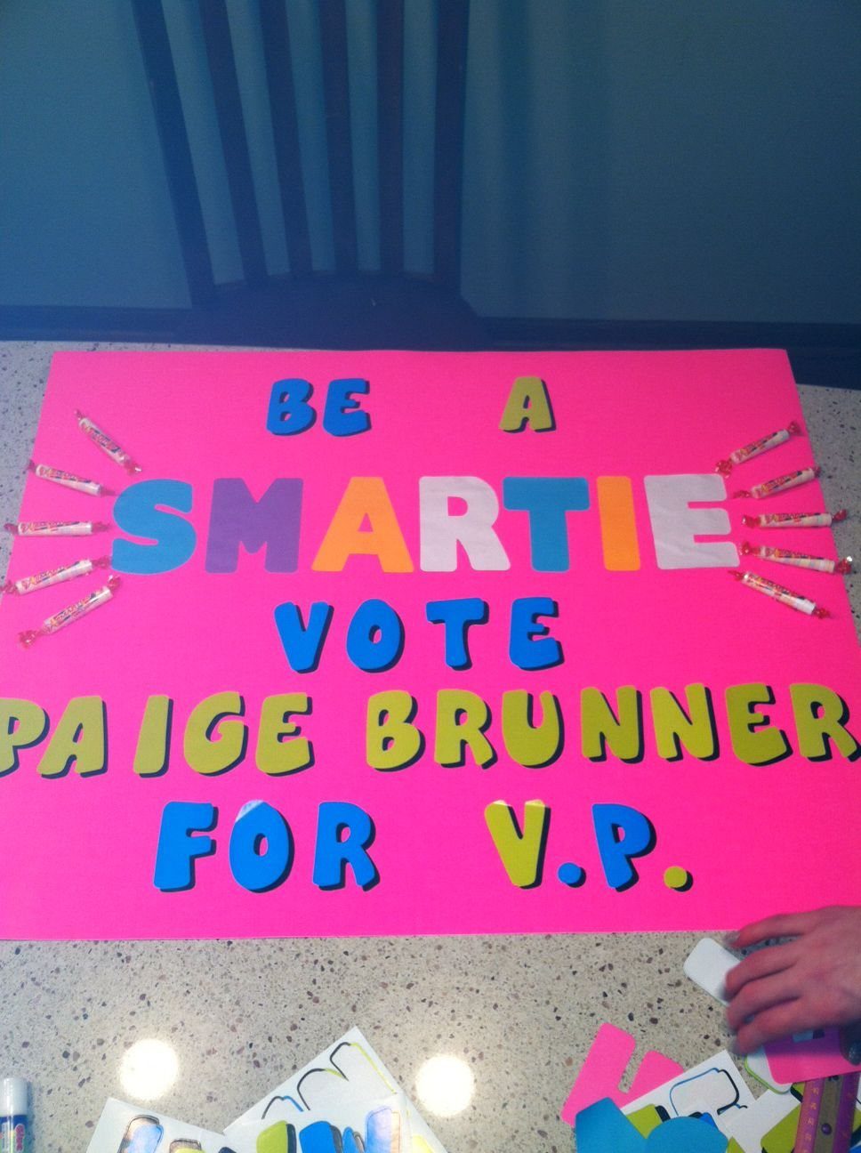 Pink campaign poster with colorful block letters and candies attached to the sides.