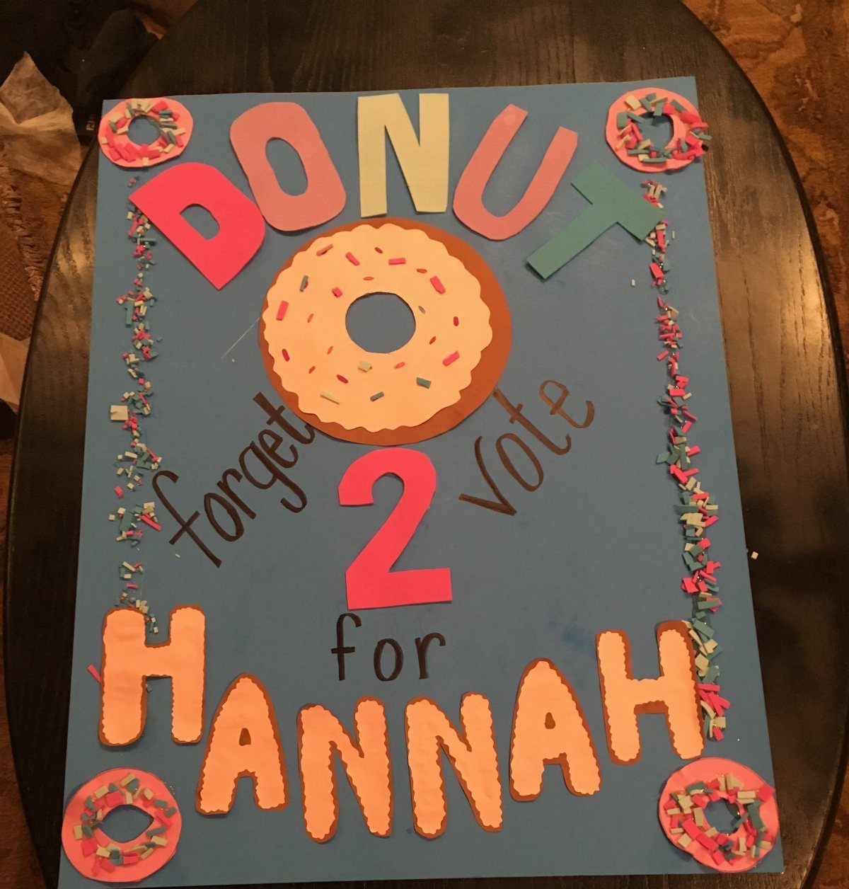 Blue campaign poster with donut cutouts and text voting for Hannah