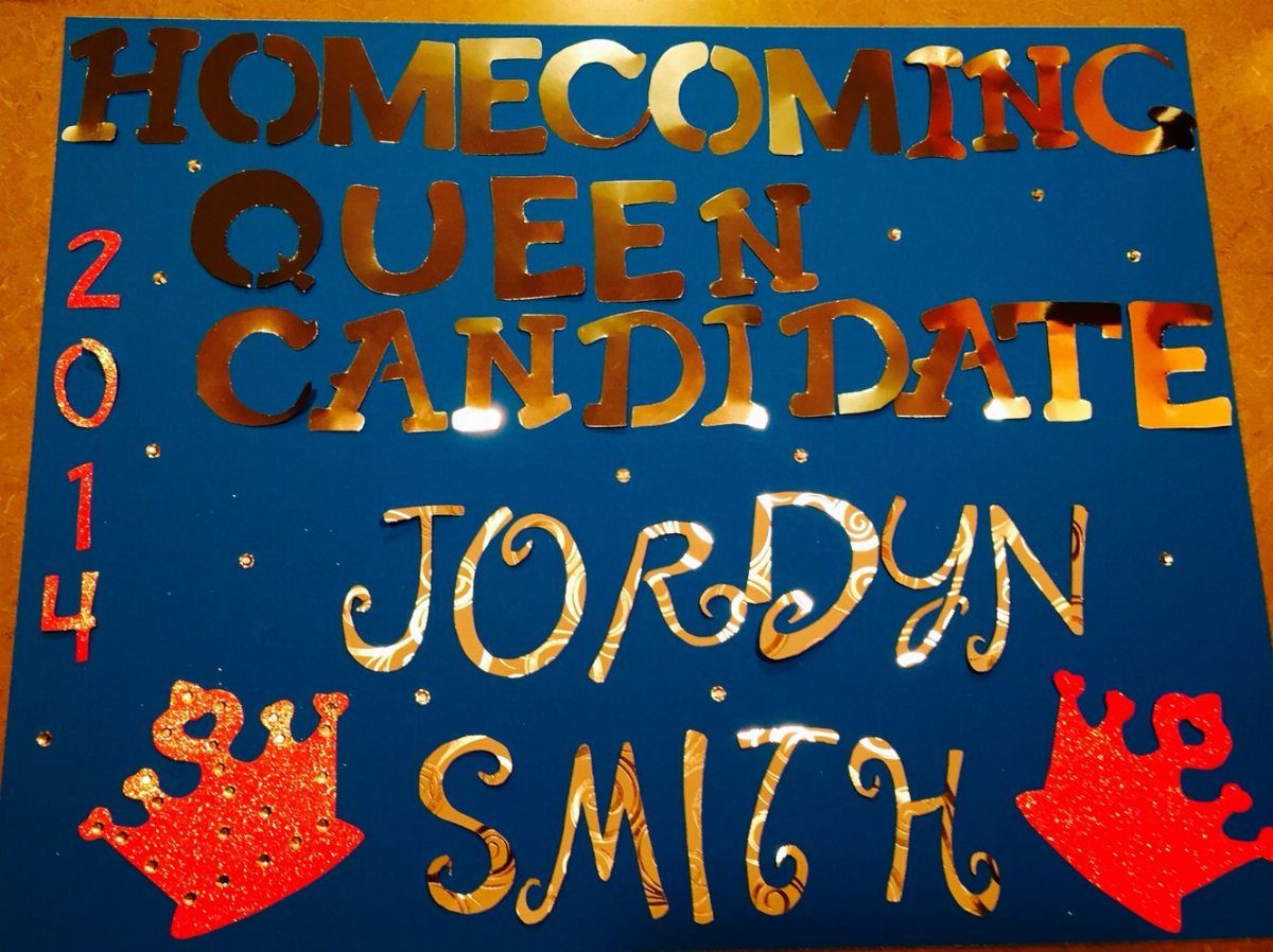 Blue homecoming queen candidate poster with gold reflective letters and red glittery crowns.