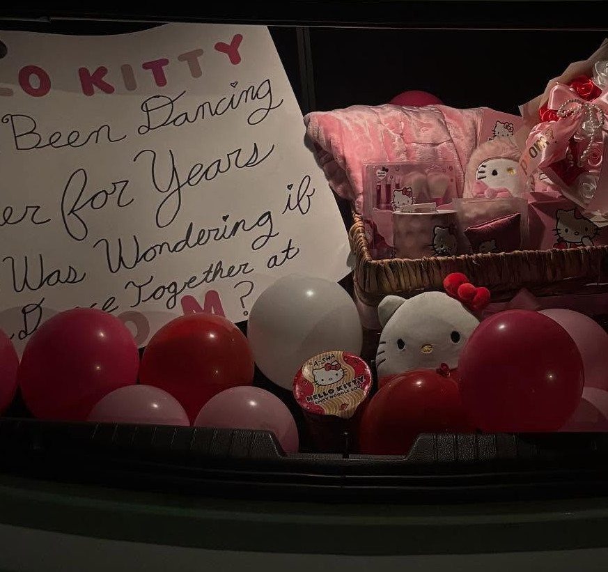 Promposal setup with Hello Kitty themed gifts, pink balloons, and a handwritten sign.