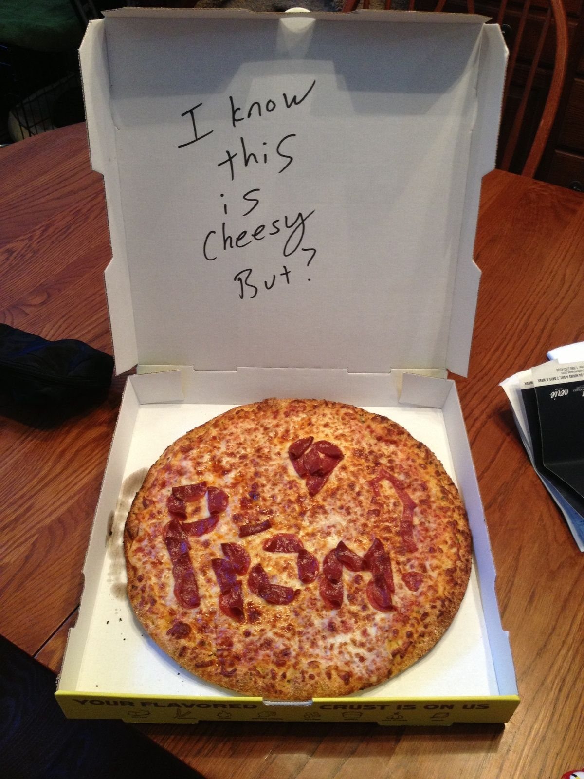 Pizza in a box with pepperoni spelling PROM and a cheesy pun message.
