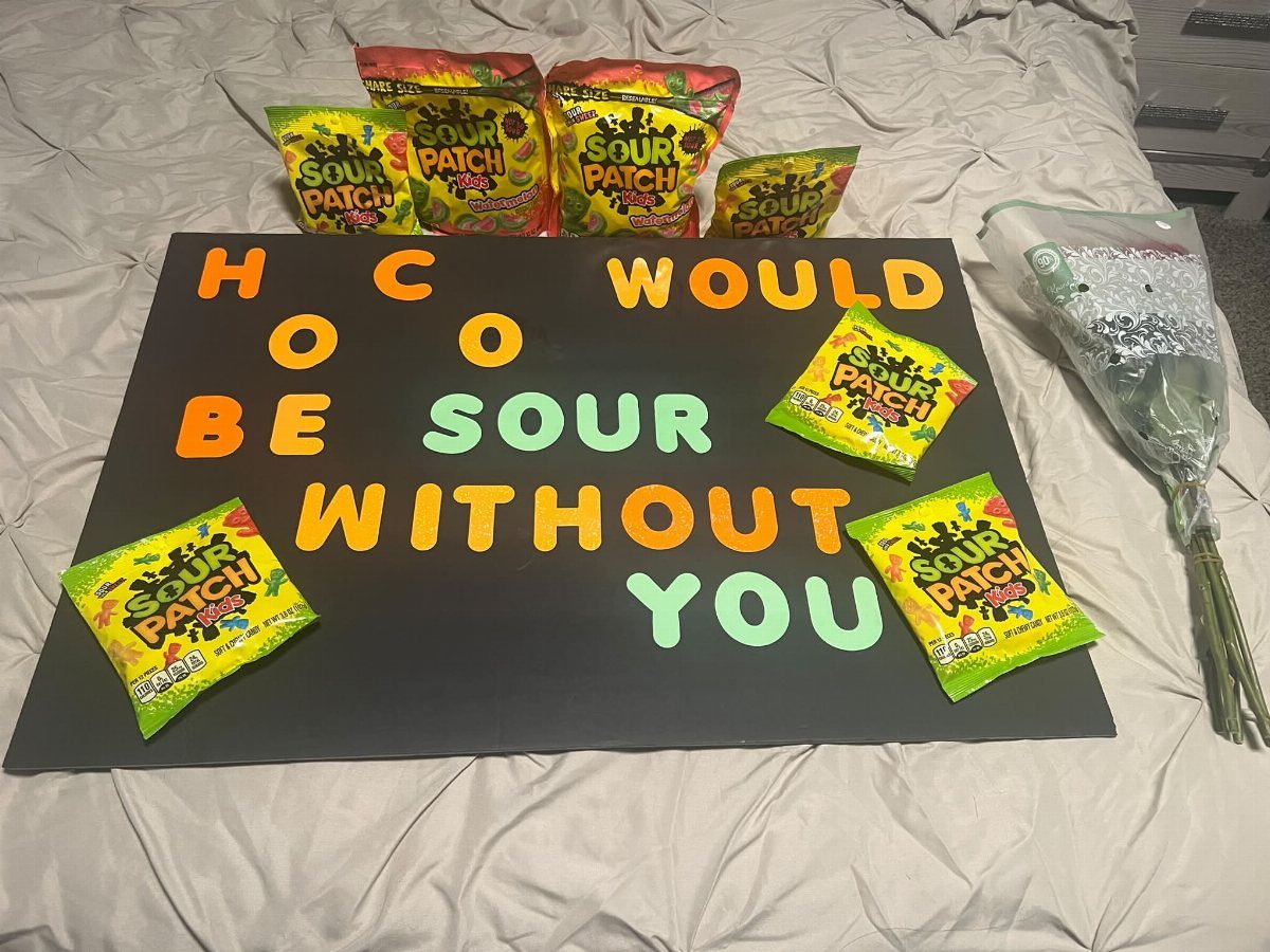 Black homecoming proposal poster with Sour Patch Kids candy and a flower bouquet.