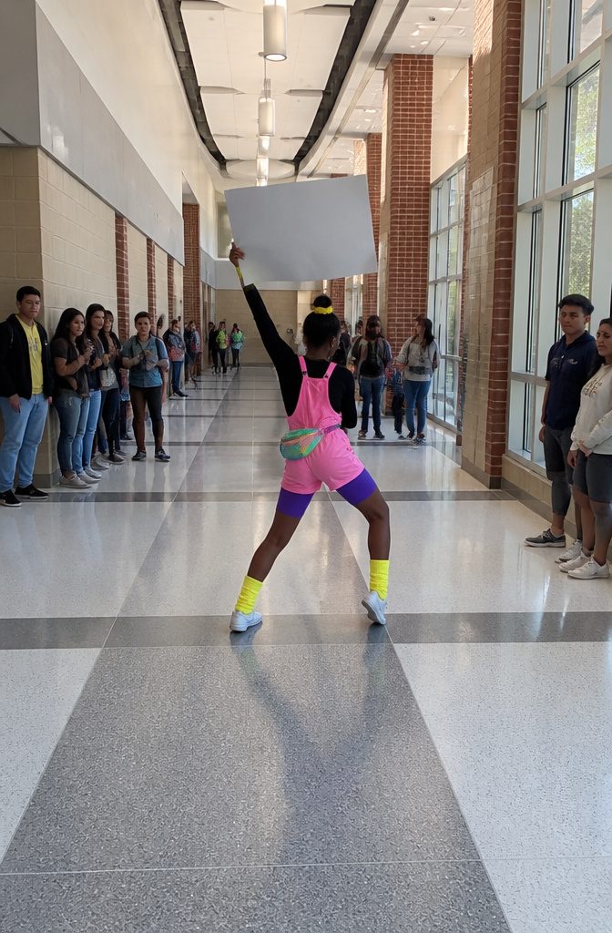 A person dancing with a sign in front of a camera.