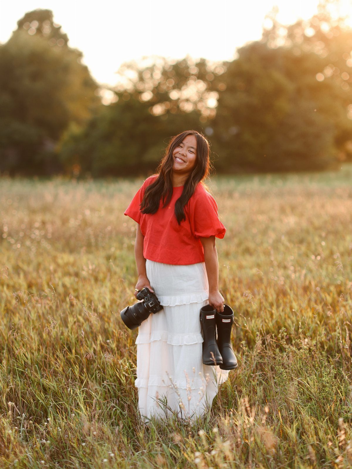 Smiling woman in red top and white skirt standing in a golden field