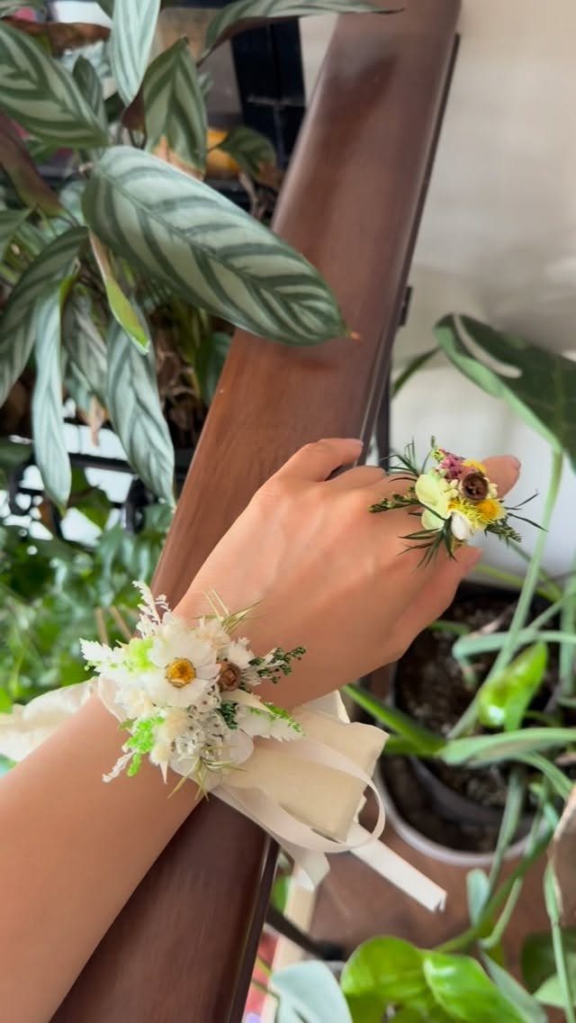 White floral corsage on a wrist and a matching small flower arrangement.