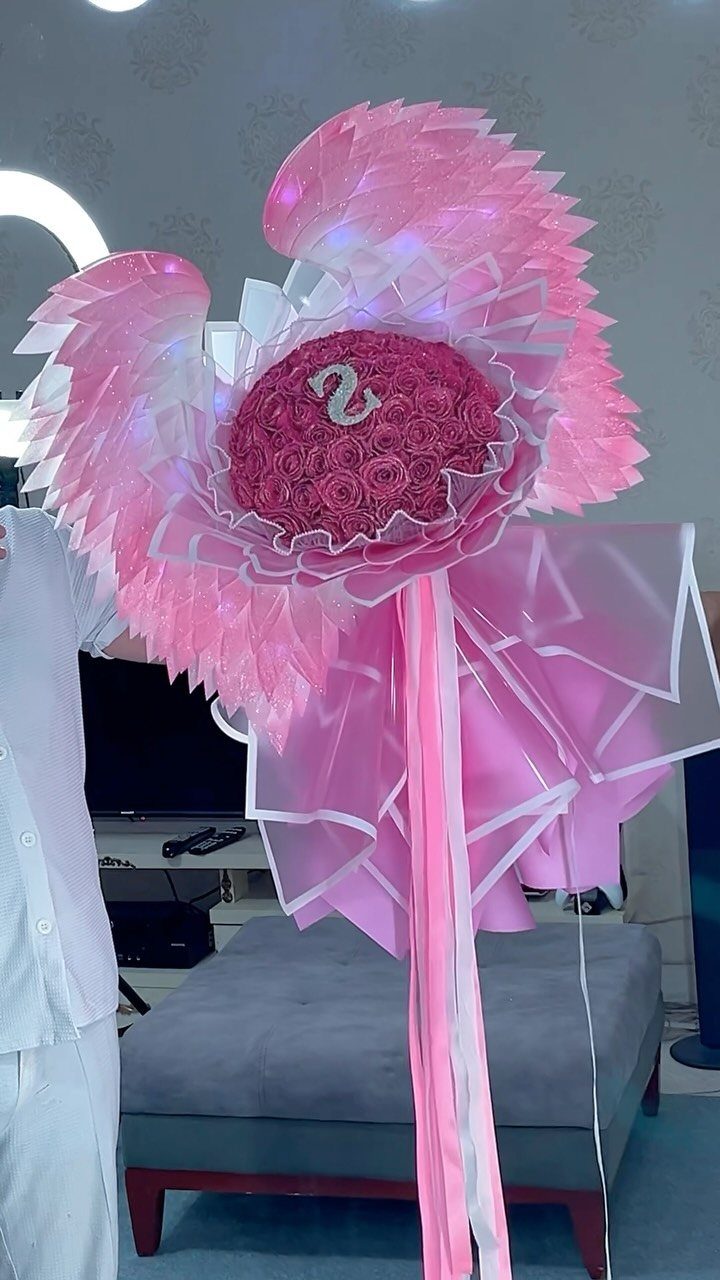 Wing-shaped pink rose bouquet with a number two in a living room