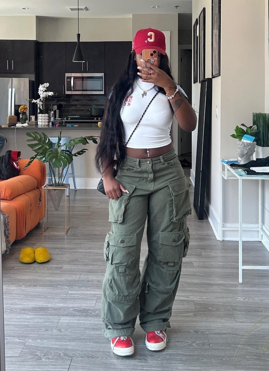 Woman wearing a white cropped tank top and olive green cargo pants with red sneakers.