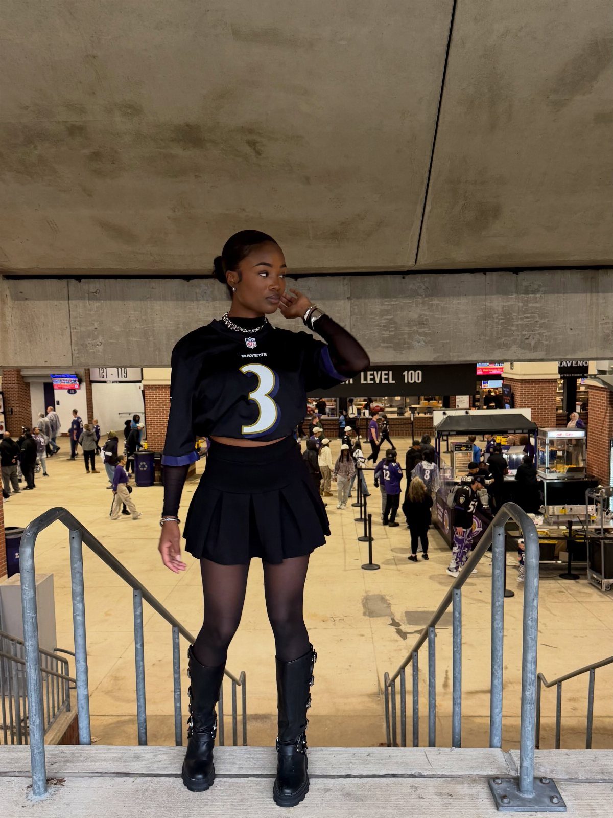 Woman wearing a navy football jersey and black pleated mini skirt at a stadium