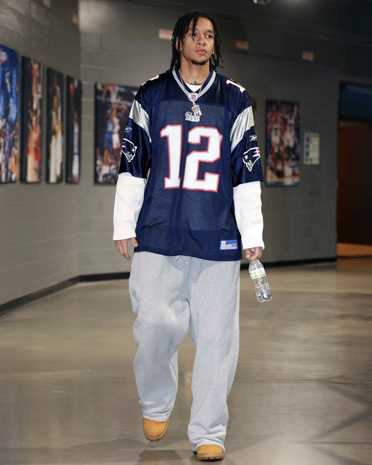 Man wearing a navy football jersey and grey sweatpants walking in a hallway