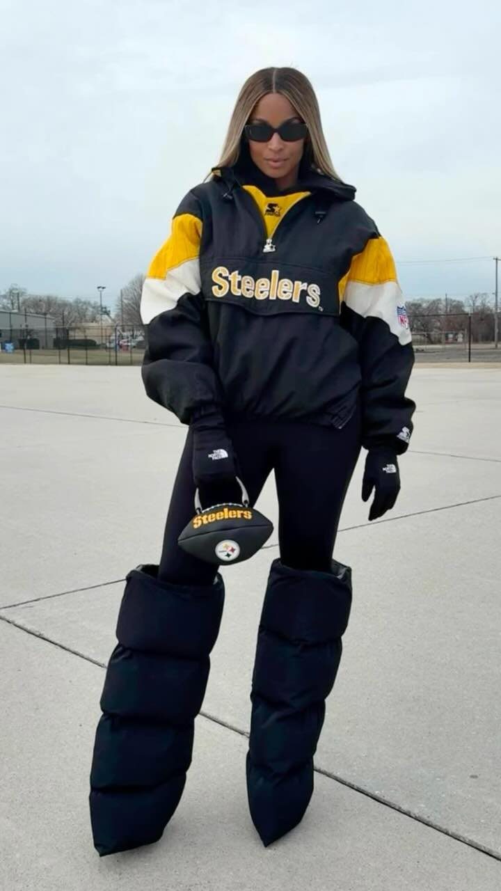 Woman in Steelers windbreaker and puffer boots holding a football outdoors