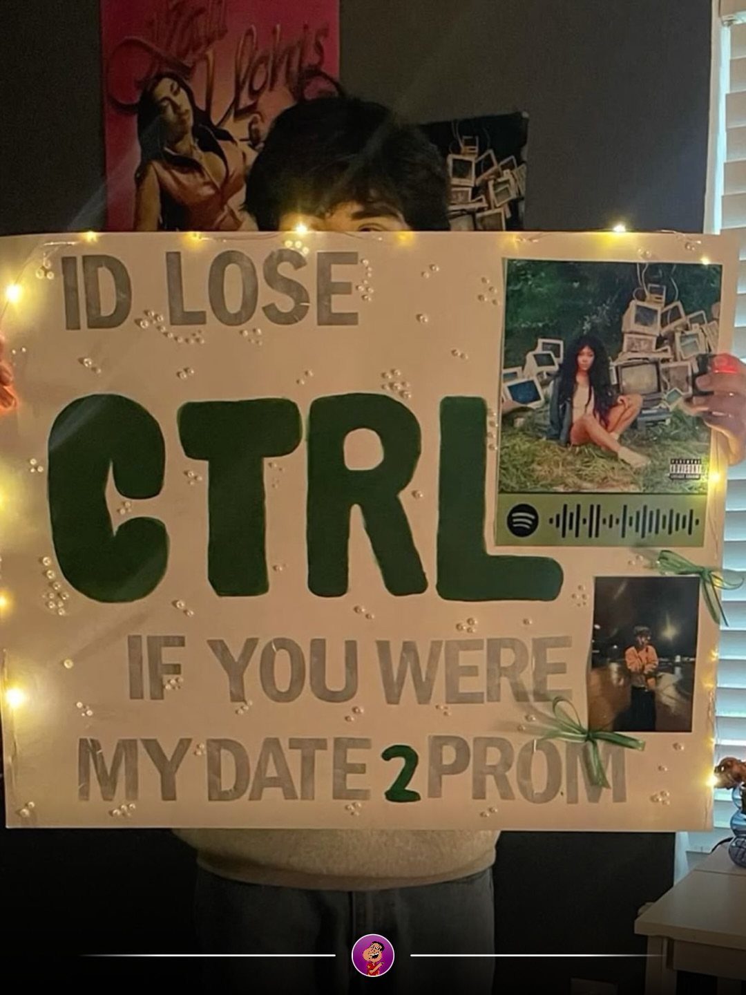 Person holding a prom proposal poster with green text and fairy lights.