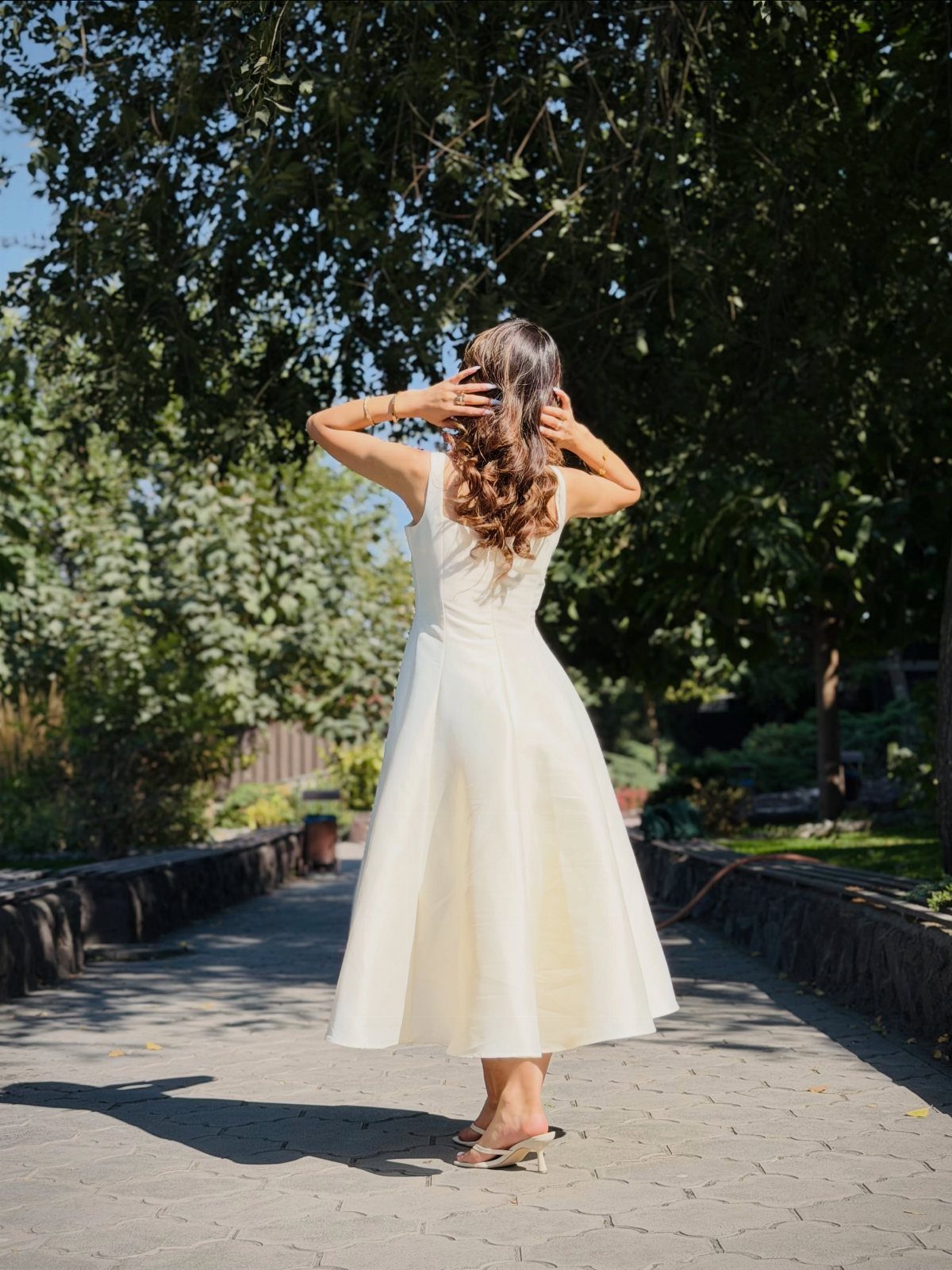 Woman from behind wearing a white midi dress and heels on a path