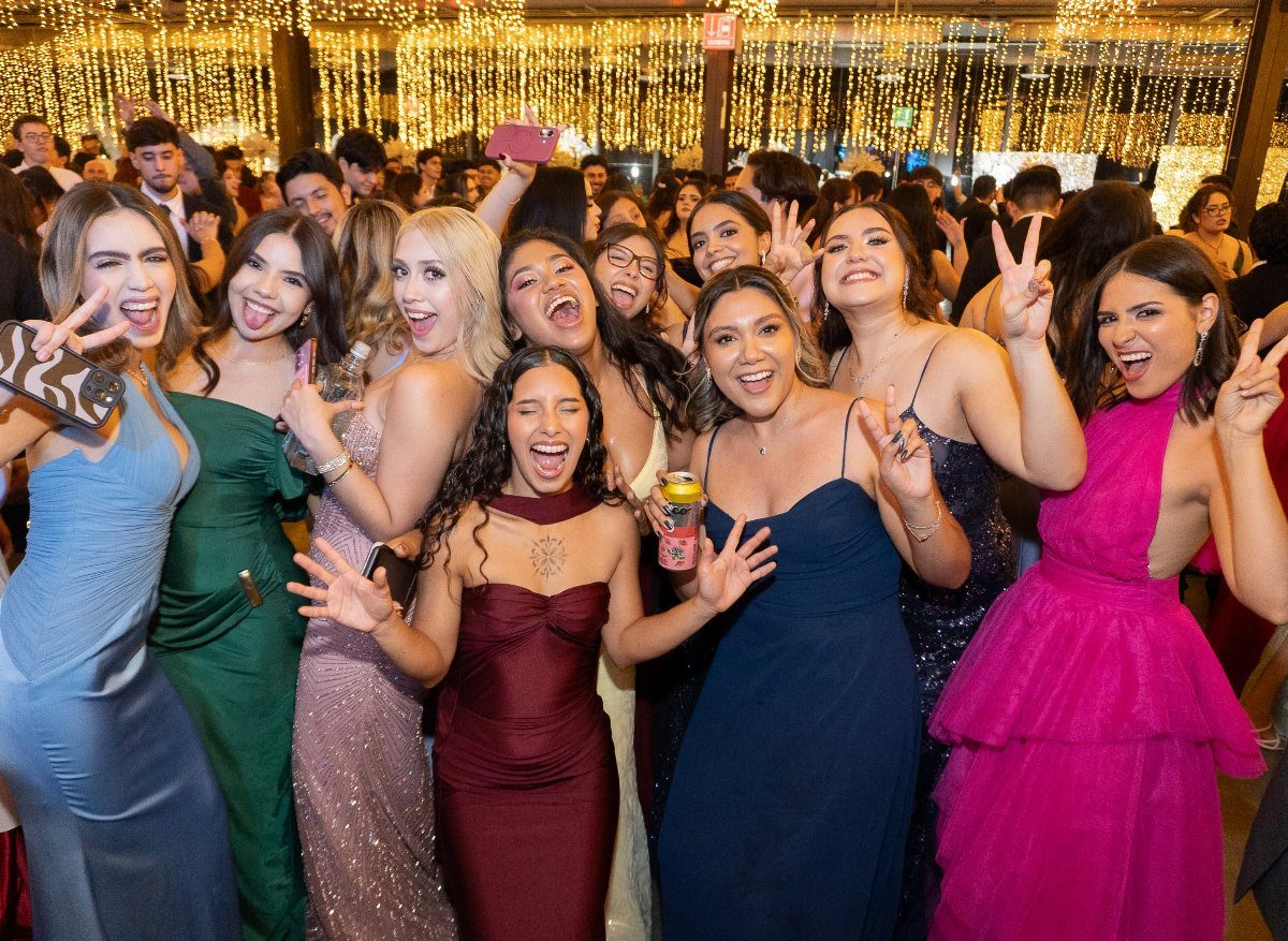 Group of young women in formal gowns smiling at a celebratory party event.