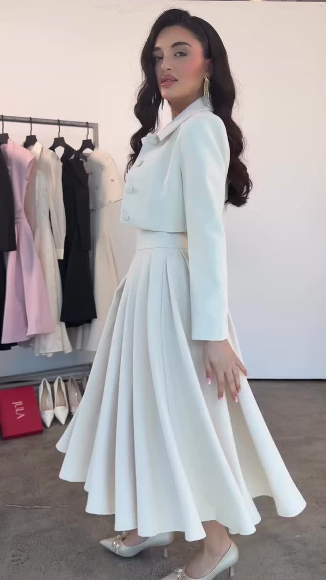 Woman wearing a white midi dress and matching cropped jacket in a boutique