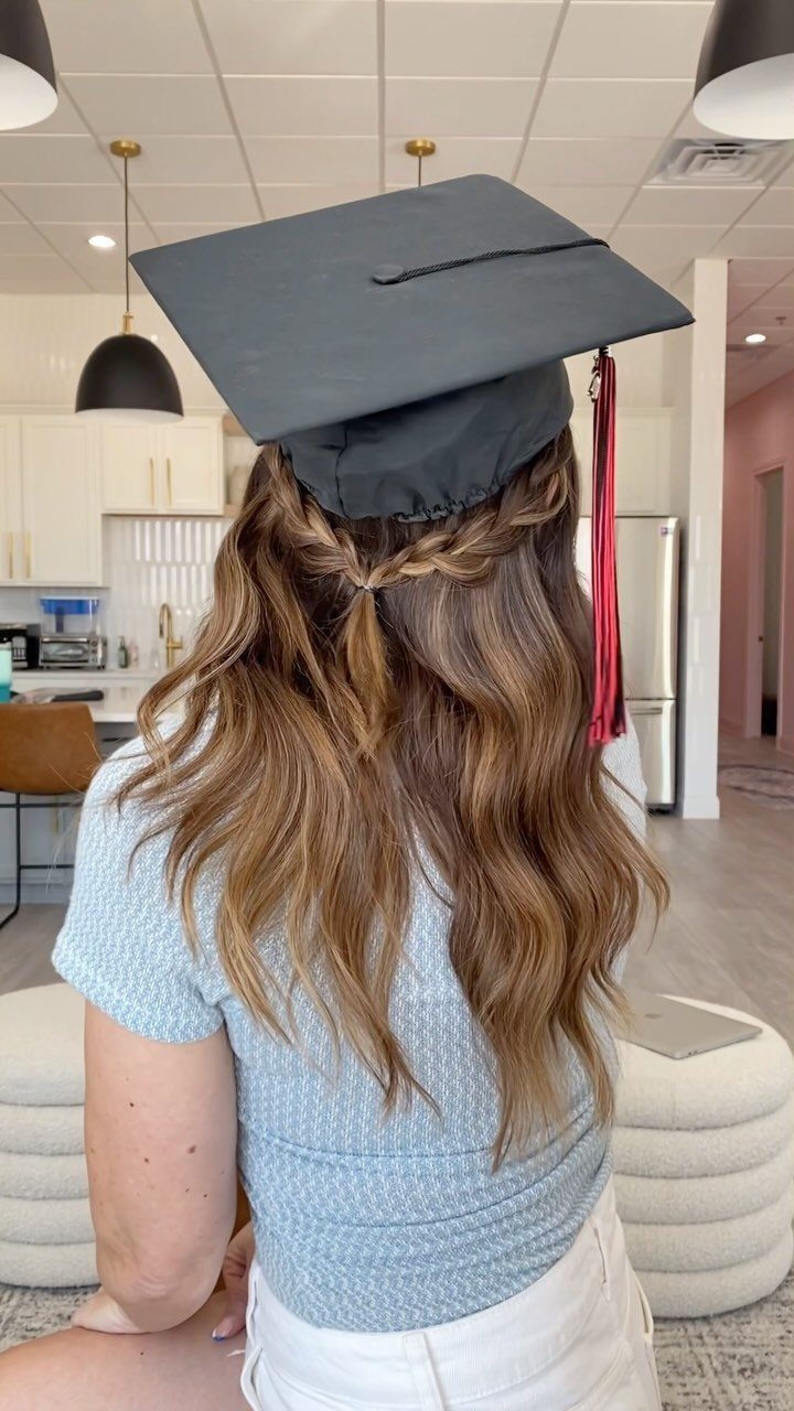 Woman with long wavy brown hair in a braid wearing a graduation cap.