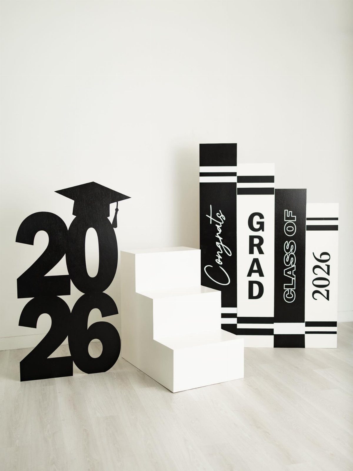 Graduation photo booth setup with 2026 numbers, white steps, and giant book props.