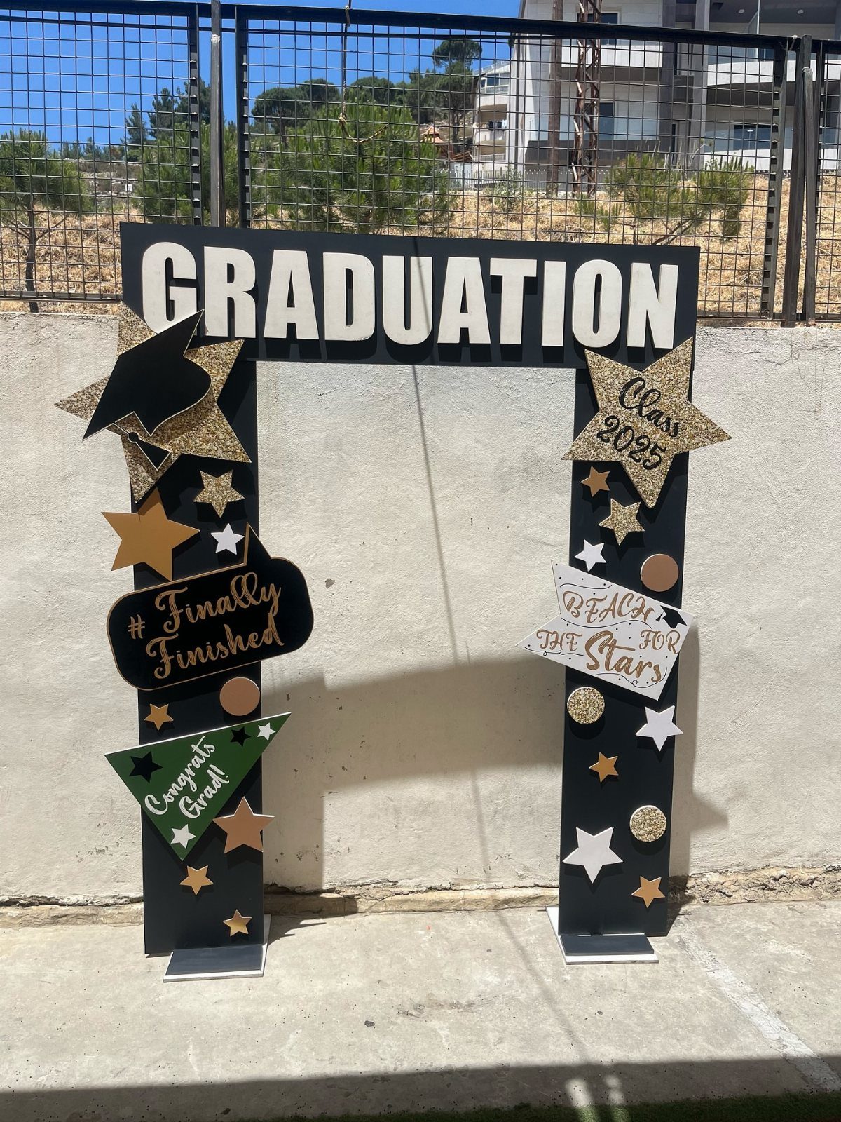 Graduation photo booth frame with gold stars and celebratory signs against a white wall