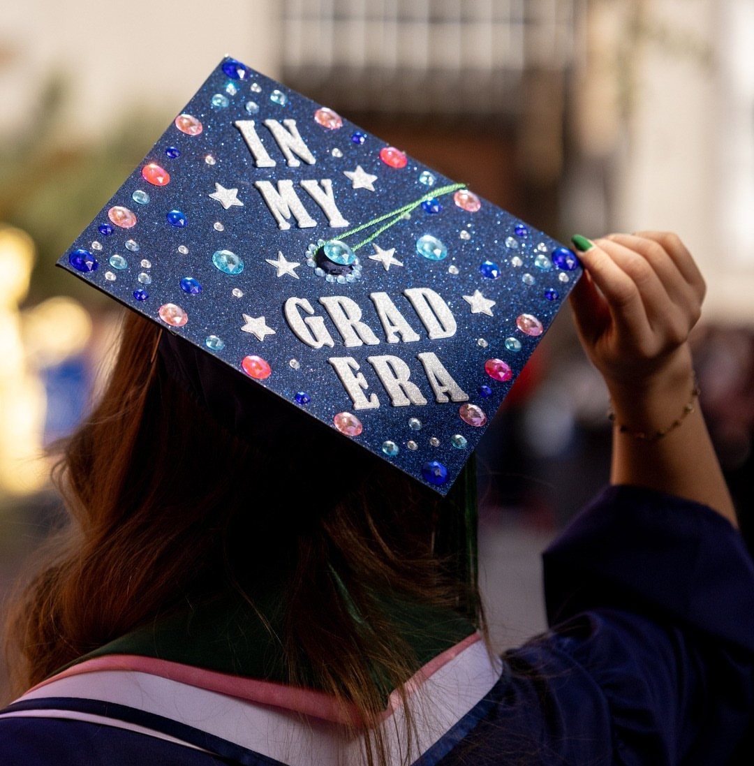 Woman from behind wearing a decorated graduation cap that says In My Grad Era