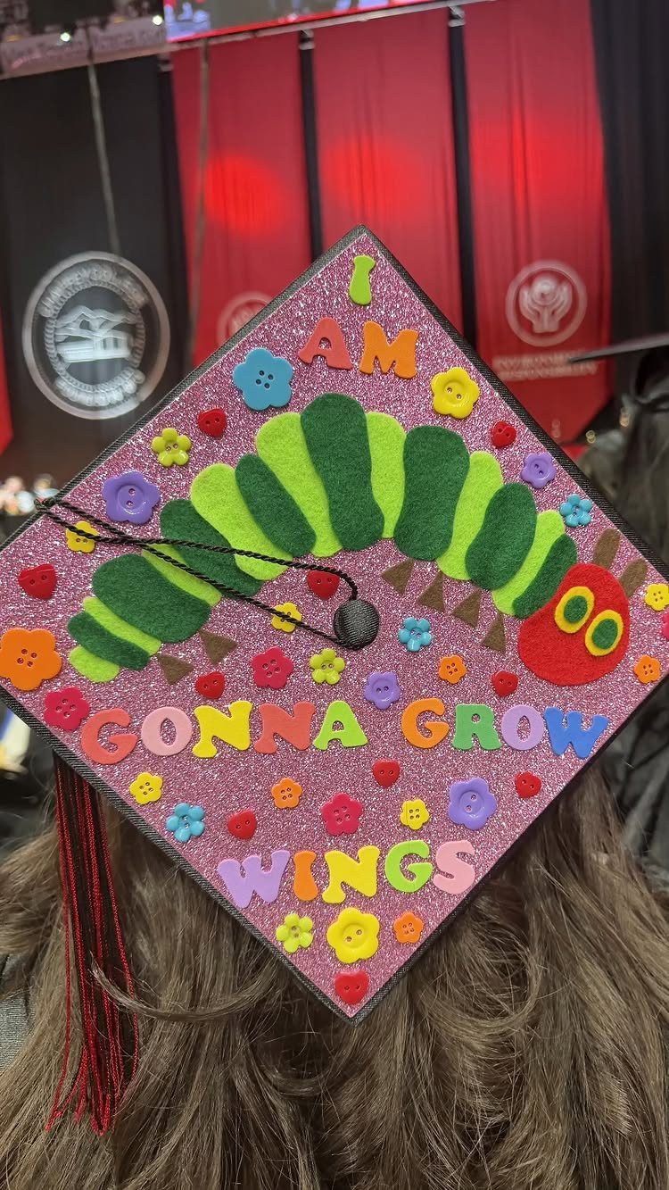 Decorated pink glittery graduation cap featuring a green felt caterpillar and colorful letters.