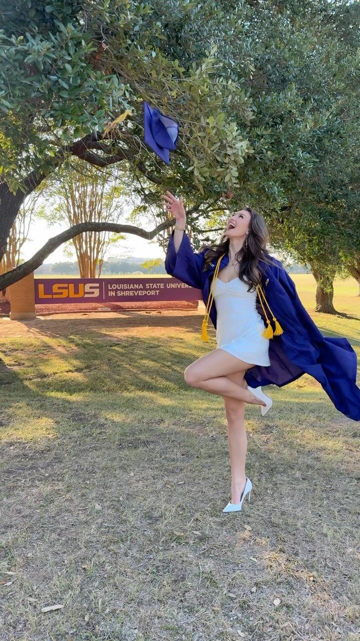 Woman in blue graduation gown tossing her cap in the air on campus
