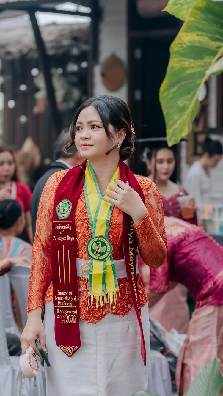 Woman in traditional attire wearing a graduation stole posing outdoors for a portrait