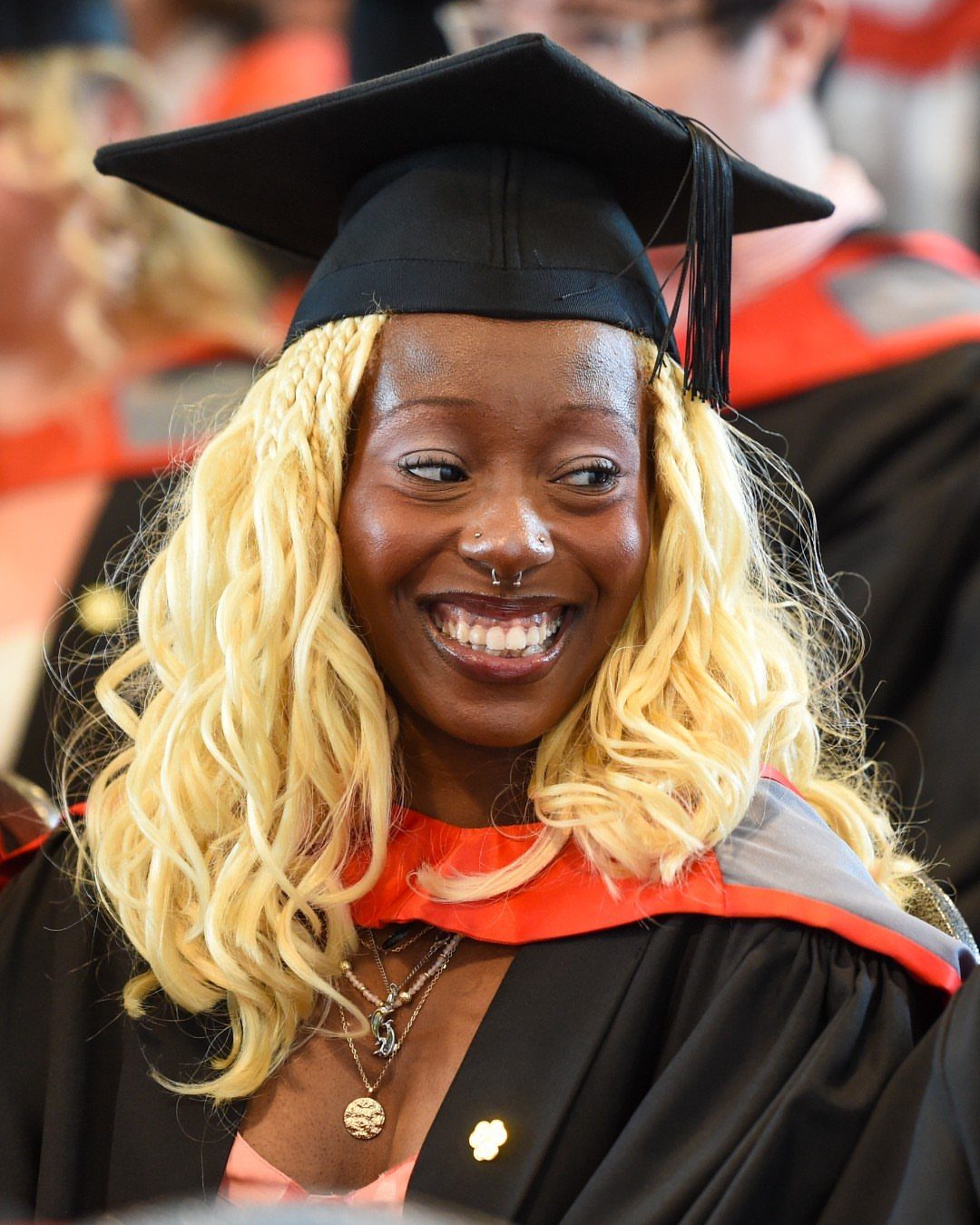 Smiling woman with blonde hair wearing a black graduation cap and gown.