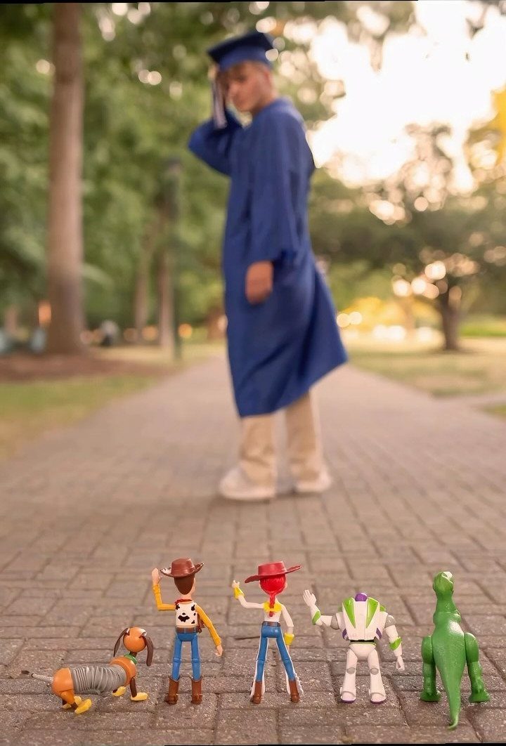 Toy Story figures standing on a brick path with a graduate in background