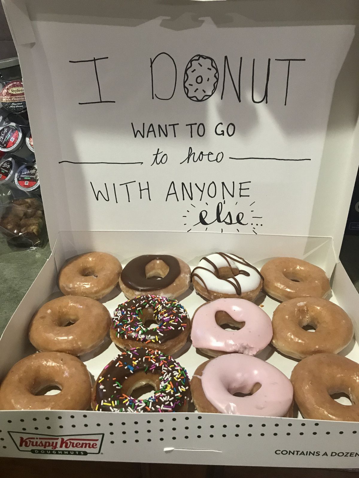 Open donut box with a handwritten homecoming proposal message on the inside lid.
