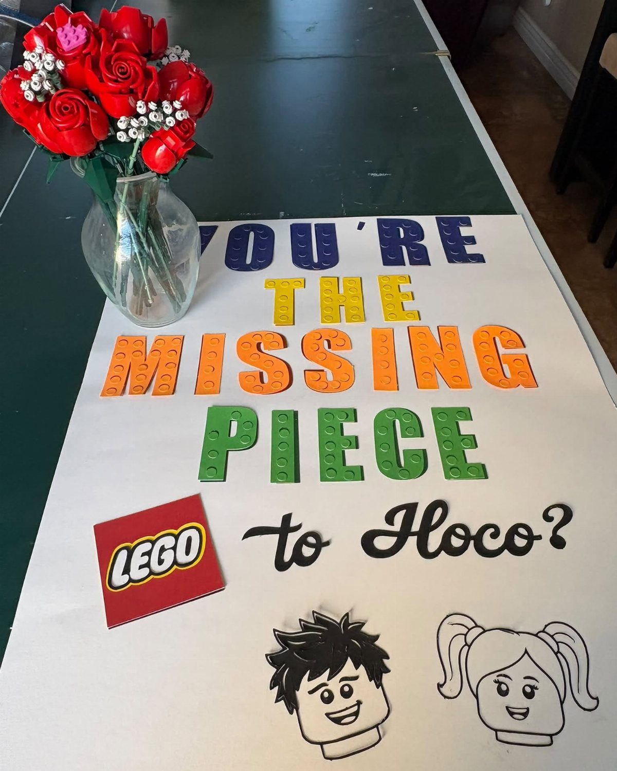 White poster with LEGO brick letters asking to Hoco next to red roses.
