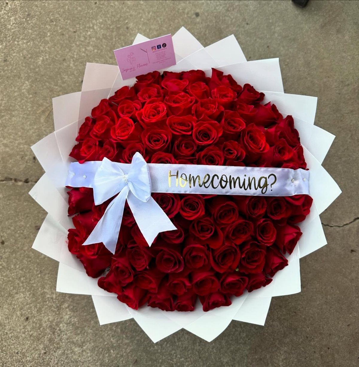 Large bouquet of red roses with a white ribbon saying Homecoming?