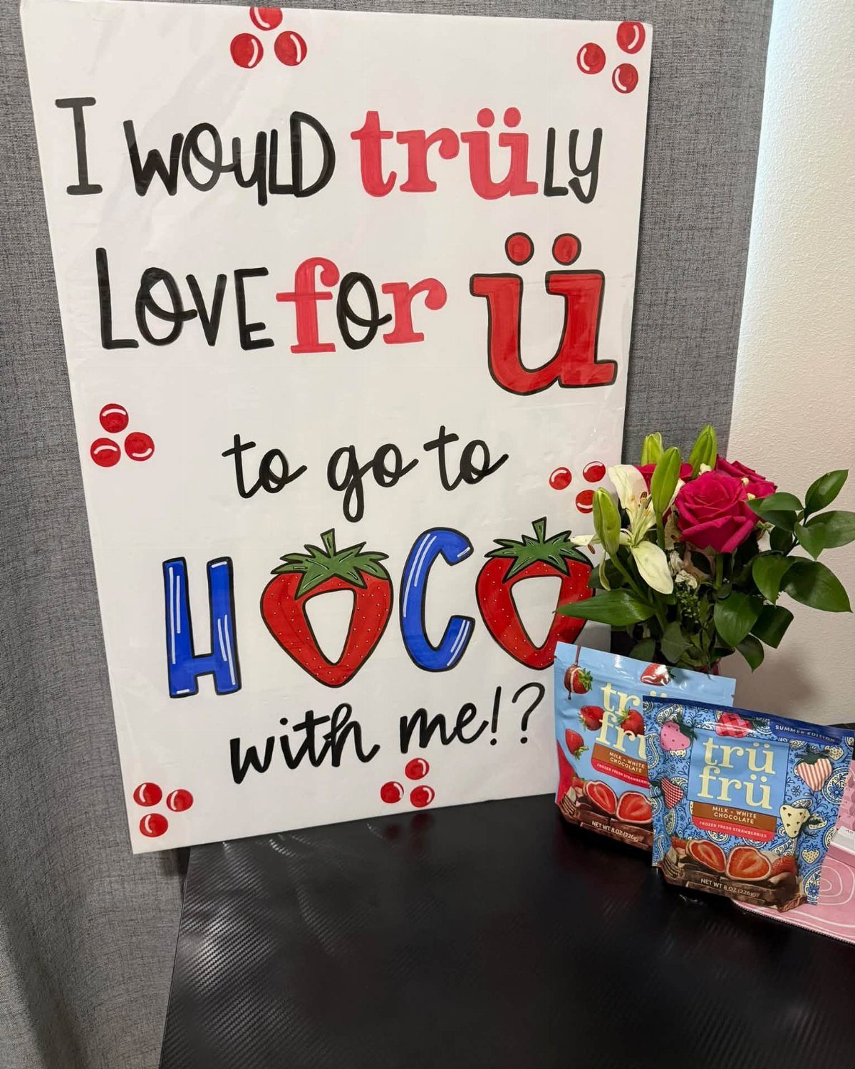 Homecoming proposal poster with strawberry puns, red roses, and strawberry snacks.