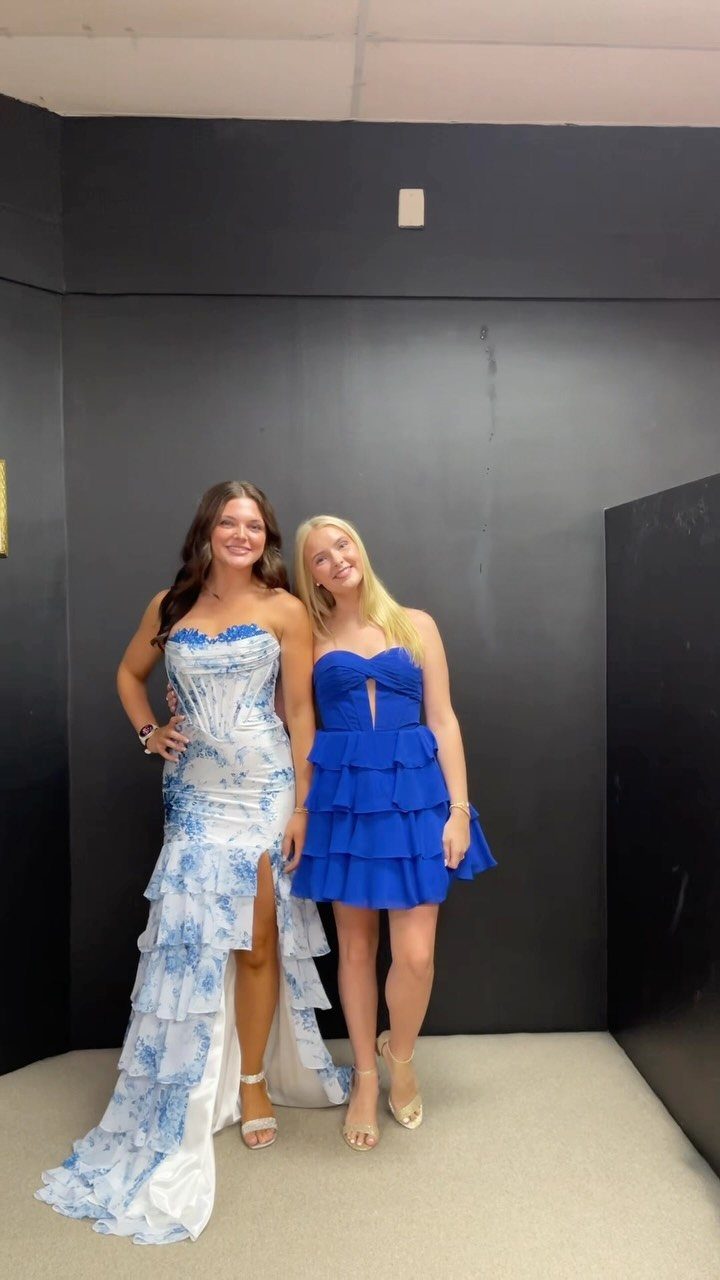 Two women posing, one in a long blue and white floral gown.