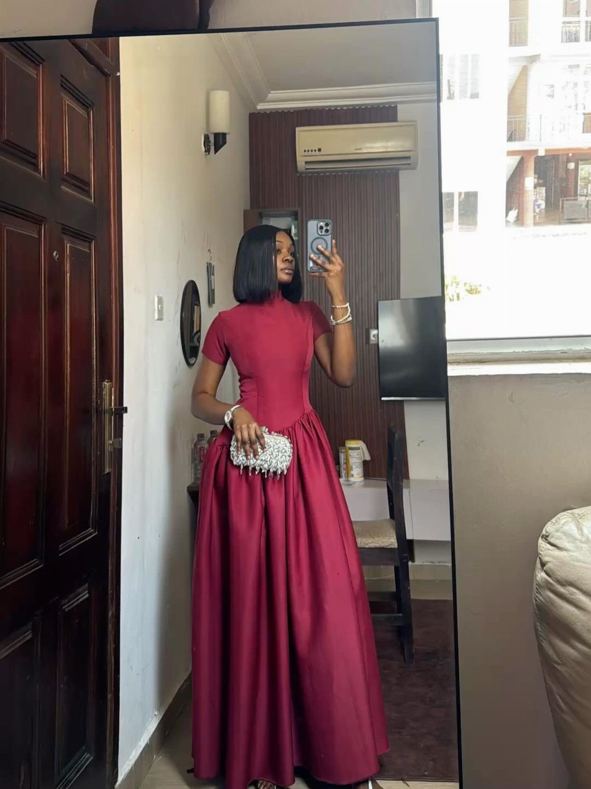 Woman in a burgundy A-line satin gown with short sleeves and high neckline.