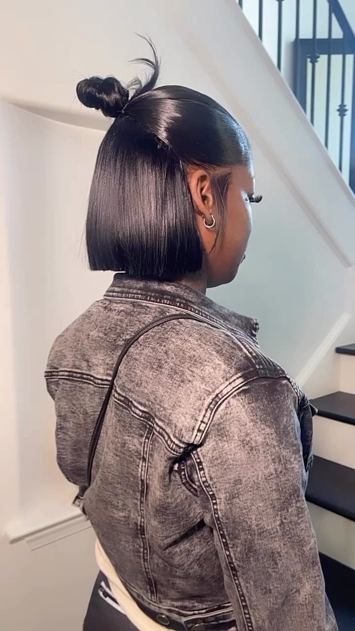 Sleek black short bob with a small half-up bun and grey denim jacket.