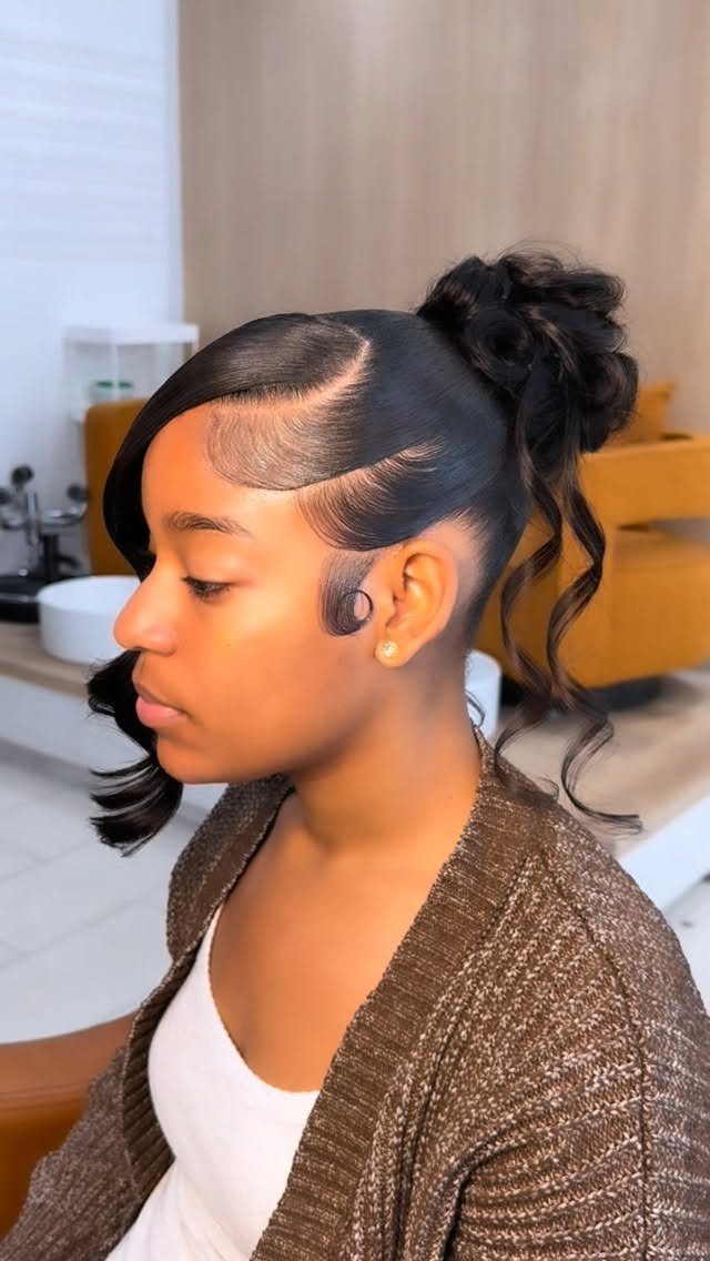 Young woman with short black hair styled in a high curly bun and bangs.