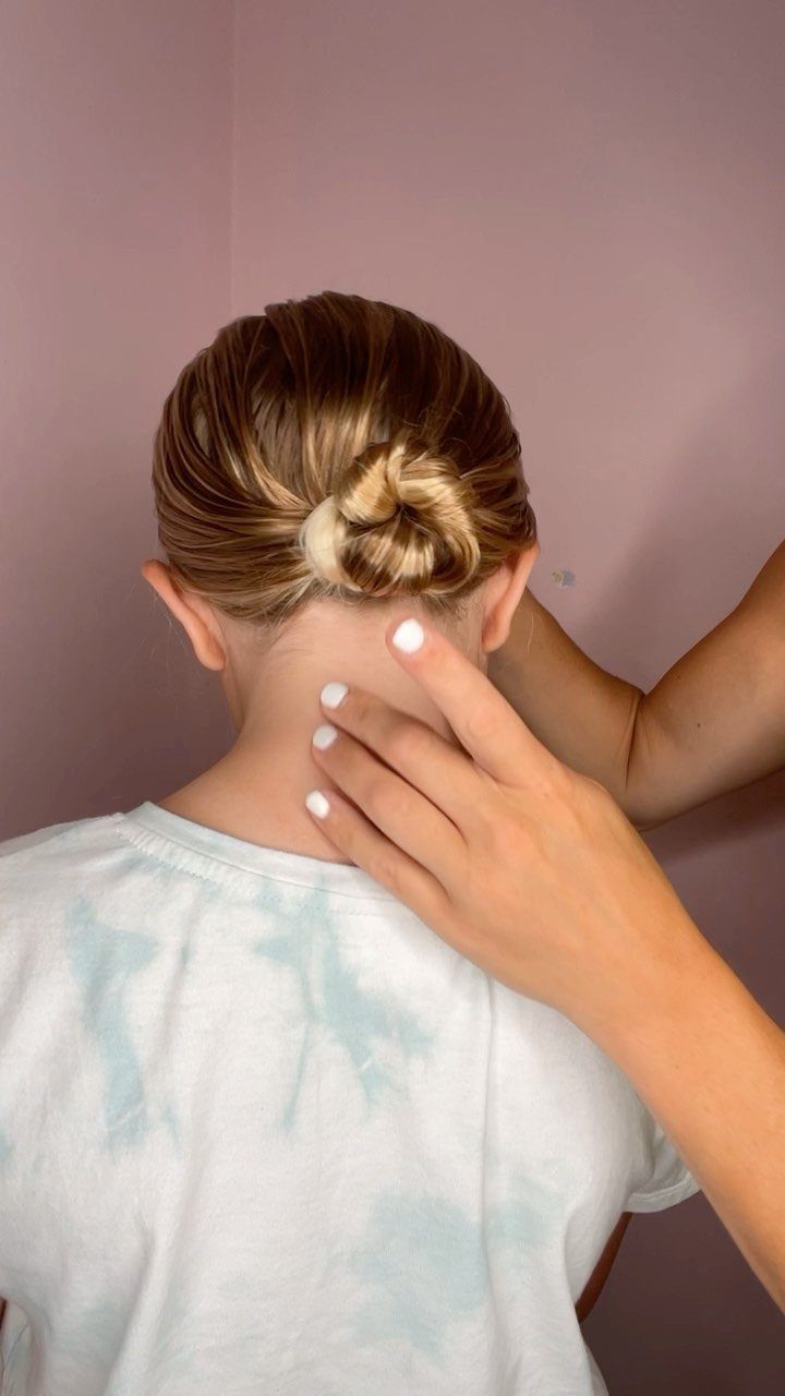 Blonde hair styled into a small knotted updo at the nape of the neck.