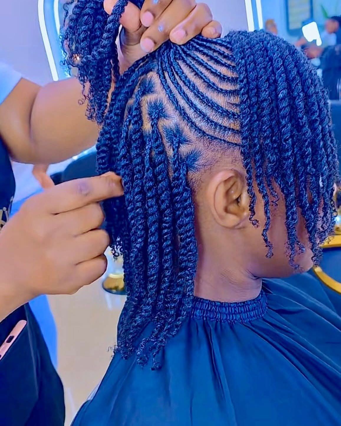 Short black hair styled in intricate twists and cornrow braids at a salon.