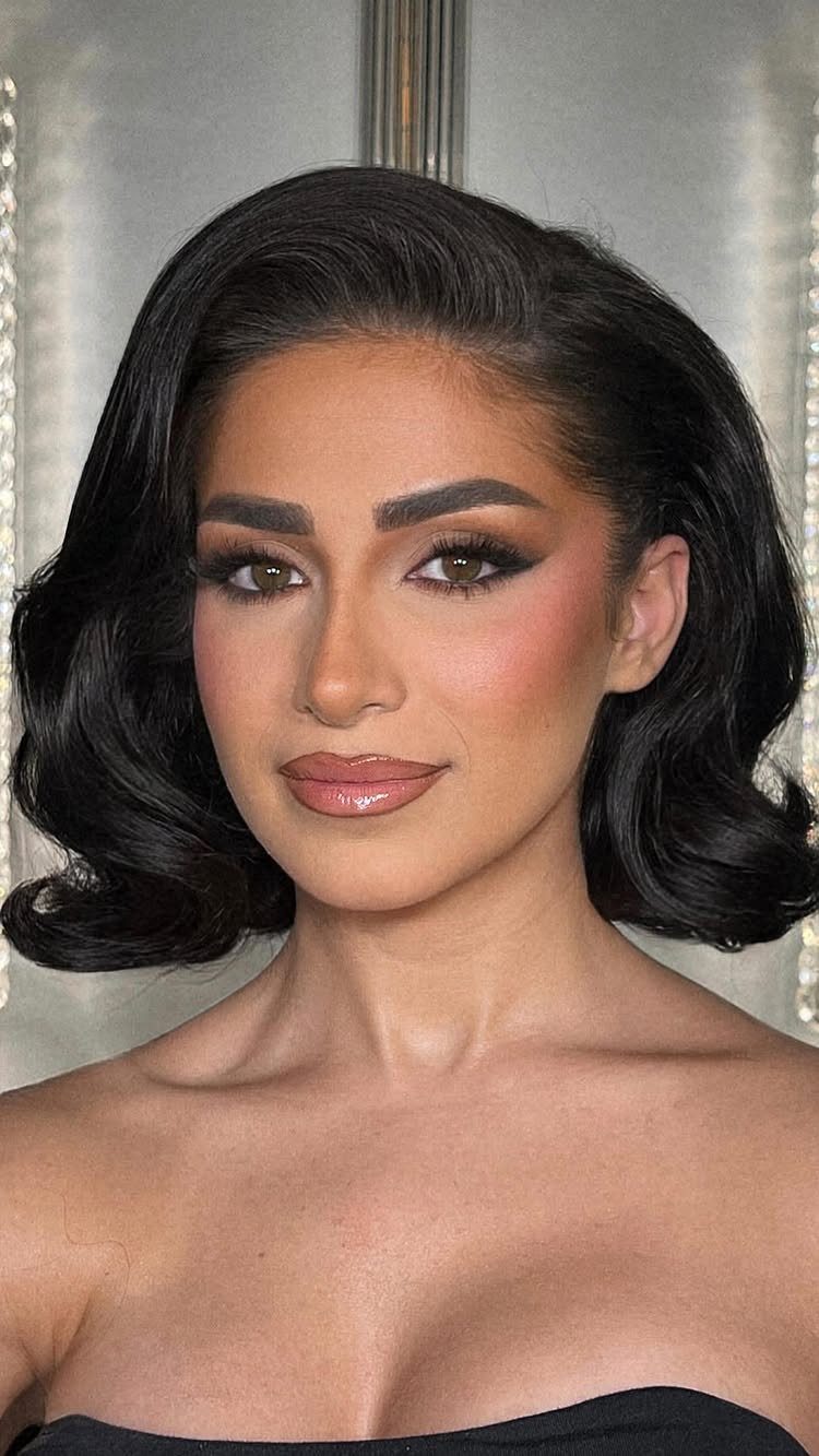 Woman with short dark hair styled in vintage waves and glamorous makeup.