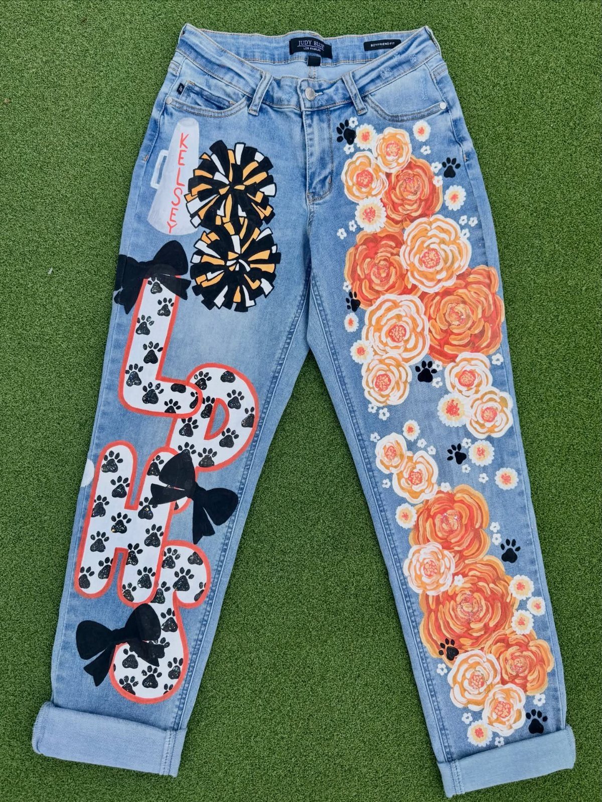 Light wash blue jeans with orange floral patches and custom letter designs